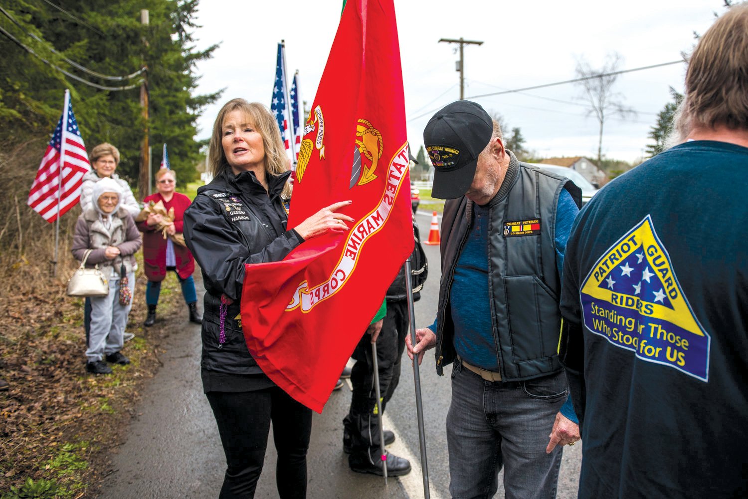 Marine Corps veteran Roger Flinn, right, lowers his head as Mary Astrid, center left, talks about his service before the unveiling of a "Purple Heart County" sign in the 3900 block of Harrison Avenue in Centralia in 2020.